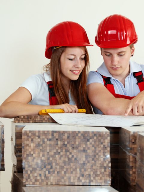 Junge Arbeiter mit Schutzhelm, die ein Haus planen