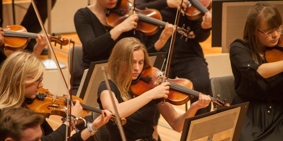 Frauen und ein Mann spielen Geige im Orchester