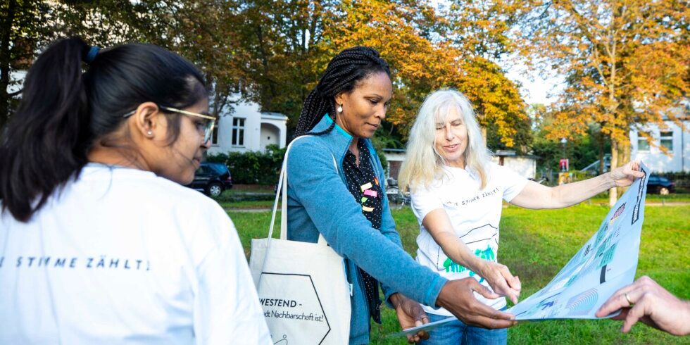 drei Frauen stehen im Park und sehen auf eine Karte
