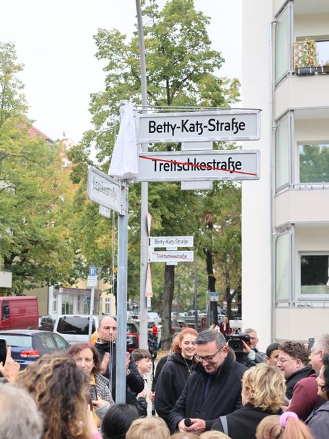 Bezirksstadtrat für Ordnung, Umwelt- und Naturschutz, Straßen und Grünflächen, Urban Aykal enthüllt mit Bürgerinnen und Bürgern und weiteren Gästen aus Politik und Gesellschaft das neue Straßenschild