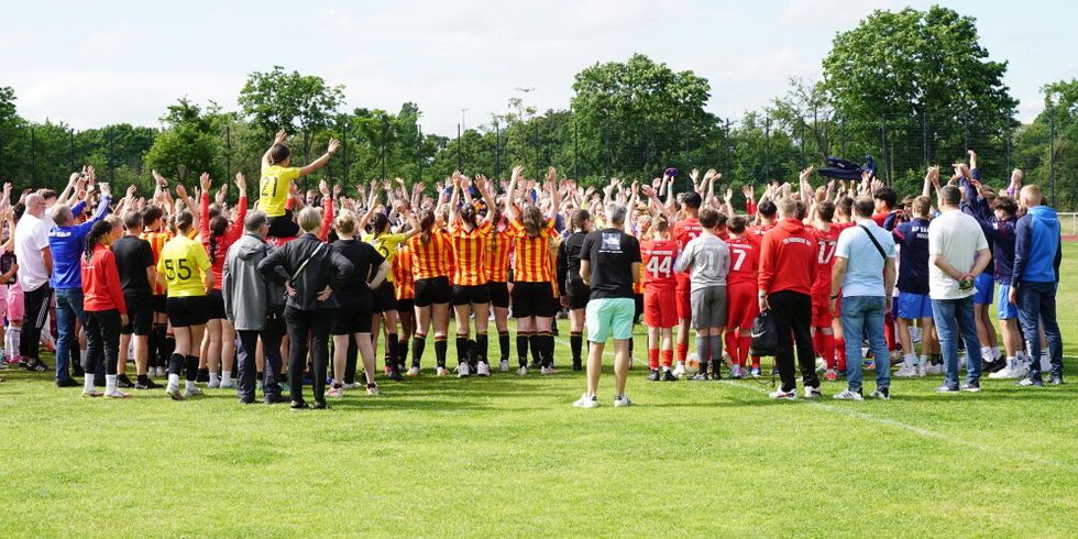 Jubelnde Junge Menschen in einer Gruppe auf grünem Rasen