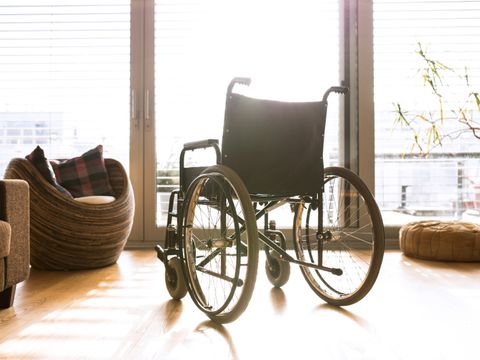 Leerer Rollstuhl im sonnigen Wohnzimmer neben der Couch