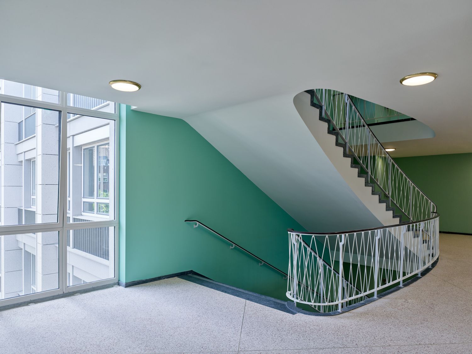 Blick auf das Treppenhaus im 4. OG nach der Sanierung mit den bauzeitlichen Deckenleuchten, Juni 2024