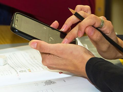 Eine Hand hält ein Smartphone, die andere Hand tippt