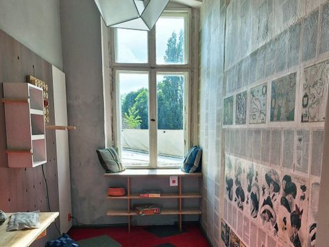 Aufnahme eines Zimmers der Zero Waste Musterwohnung mit Schreibtisch, Regalen, Sitzbank am Fenster