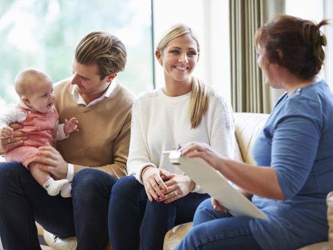 Gesundheitsbesucher sprechen mit jungem Baby mit der Familie
