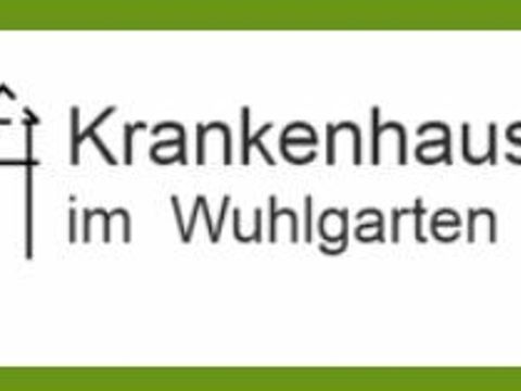 Logo der Krankenhauskirche im Wuhlgarten, ein dunkelgrauer Schriftzug mit einer stilisierten Silhouette der Kirche mit Turm in einem grünen Rahmen
