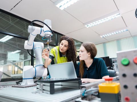 Zwei engagierte junge Ingenieurstudentinnen arbeiten im Team und befassen sich mithilfe eines Roboterarms mit der Robotertechnologie.