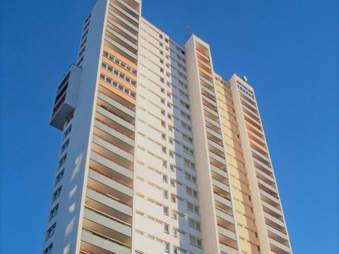 Ein weißes Hochhaus vor einem wolkenfreien blauen Himmel