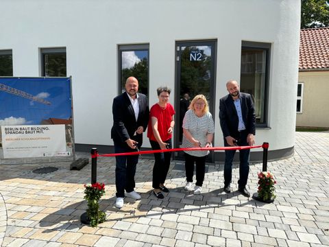 Bezirksbürgermeister Frank Bewig, Schul- und Sportamtsleiterin Astrid Knüppel, Schulstadträtin Dr. Carola Brückner und Malek Saleh, stellv. Schulleiter der Schule am Staakener Kleeblatt, beim feierlichen Banddurchschnitt vor dem neuen Werkstattgebäude. (Bild: BA Spandau)