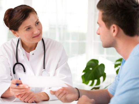 Lächelnde Ärztin überreicht jungem Patienten ein Schreiben