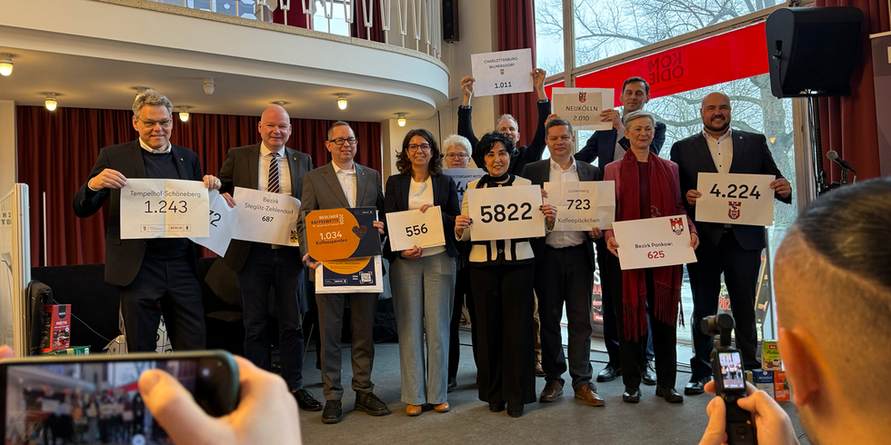 Elf Personen halten Zettel mit Zahlen in die Luft.