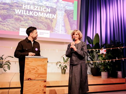 Die Moderatorin Christine Brummer (Global Goals für Berlin e.V.) und der Moderator Felix Rundel (Centre for Convening Minds) begrüßen die Anwesenden (Bild: Frank R. Schröder)