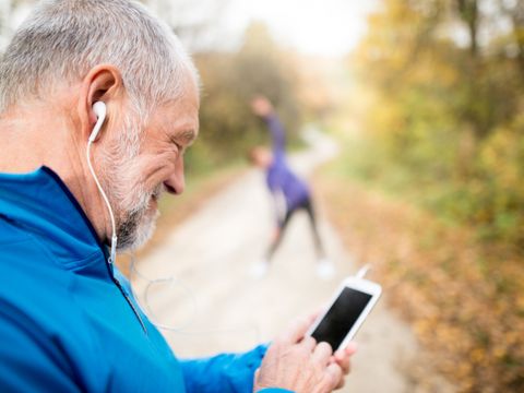 Senior runners in nature, stretching. Man with smartphone with e