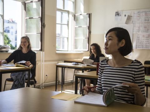 Drei Menschen hören der Kursleitenden zu