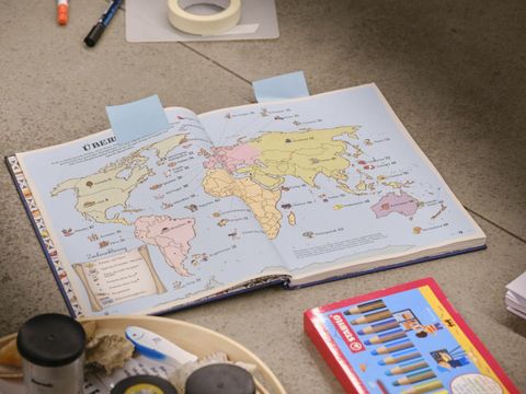 aufgeschlagener Kinder-Atlas und Bastelmaterial