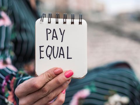 weibliche Hand hält Zettel mit Aufschrift Pay Equal
