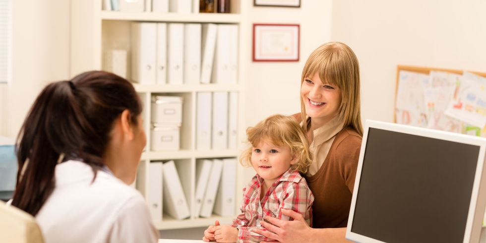 Ein Kind sitzt auf dem Schoß seiner Mutter, die mit einer Kinderärztin spricht