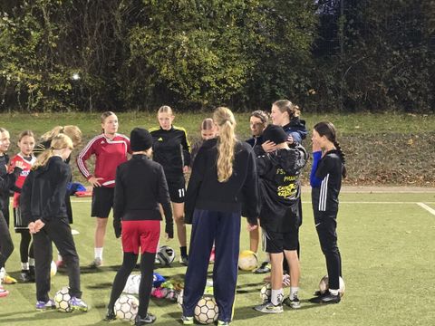 Lykka Maibaum steht im Kreis vor ihrem Team