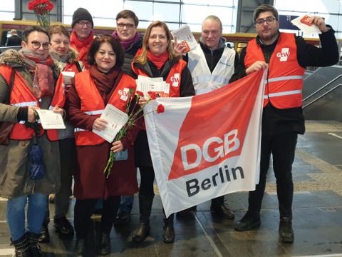 Gruppe von Menschen in DGB-Westen die eine DGB-Fahne in die Kamera halten