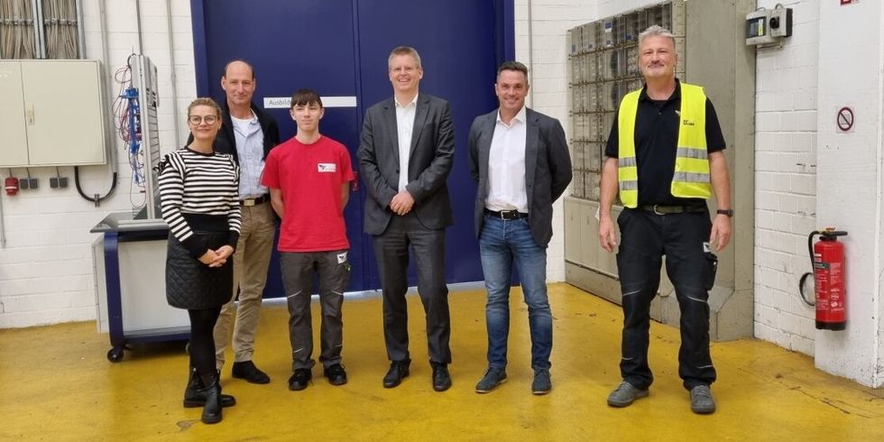 Sechs Personen stehen nebeneinander in einer Halle.