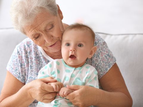 Sitzende alte Dame mit Baby, dessen Hände sie ihren hält