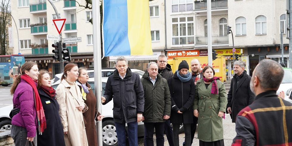eine Gruppe von Menschen steht unter einer gelb-blauen Fahne