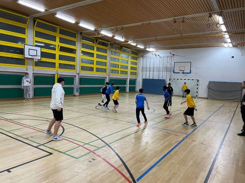 Junge Menschen spielen Fußball in einer Turnhalle