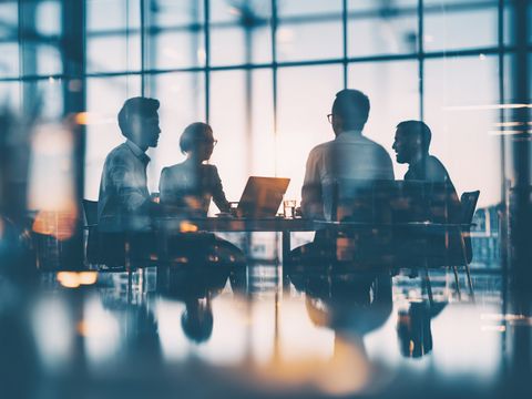 Team sitzt an Tisch im Glasgebäude