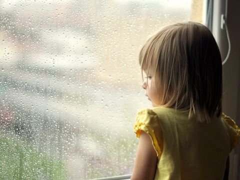 Kind stehend am verregnetem Fenster