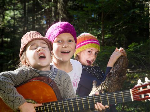 3 Mädchen sitzend und singend in einer Grünanlage