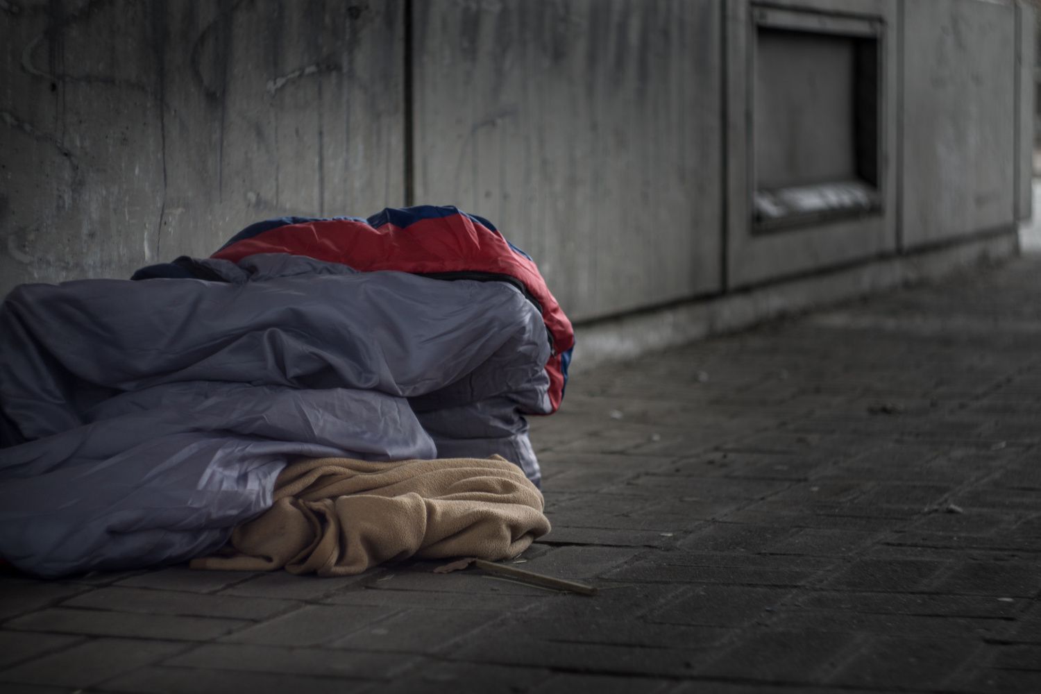 Armut auf den Straßen einer Stadt: Schlafsäcke und Decken auf dem Boden unter einer Unterführung