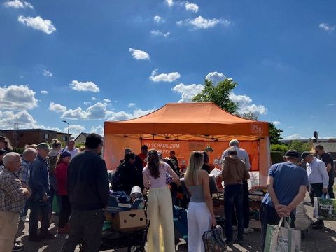 Menschen sammeln sich um ein Zelt mit Stand.