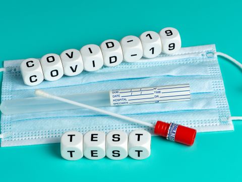Mund-Nase-Maske mit einem Abstrichset und dem Text Covid-19-Test