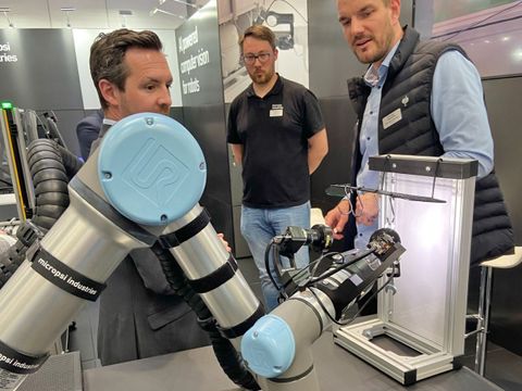Menschen betrachten einen Roboterarm bei der Arbeit