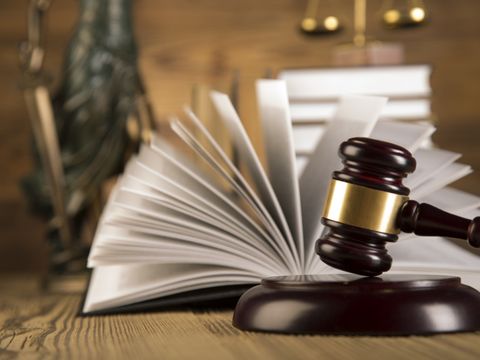 Justitia, hölzener Richterhammer und ein aufgeschlagenes Buch