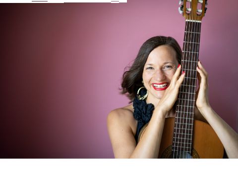 eine Frau hällt senkrecht eine Gitarre