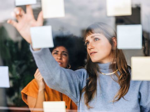 Zwei junge Geschäftsfrauen beim Brainstorming mit Haftnotizen in einem Büro