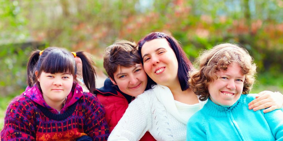 vier junge Frauen mit Behinderung lachen in die Kamera