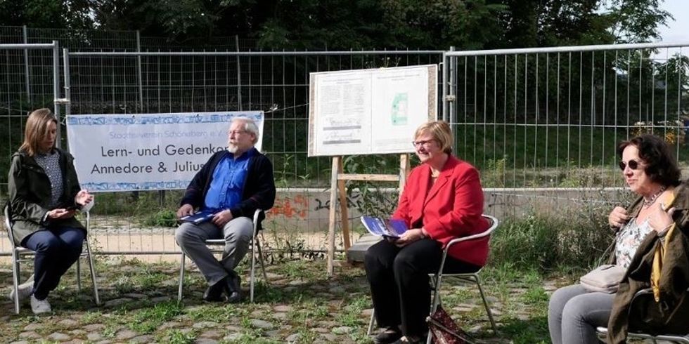 Vier Menschen sitzen im Freien auf Stühlen.