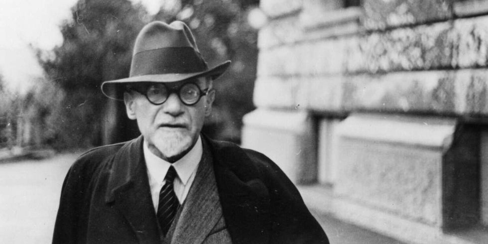 ein Mann mit Hut vor einem großen Gebäude