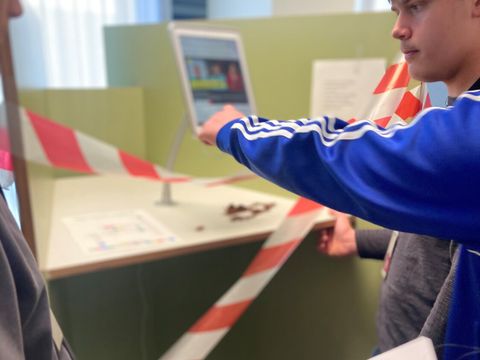 Jugendliche lösen ein Rätsel am Kundenterminal.