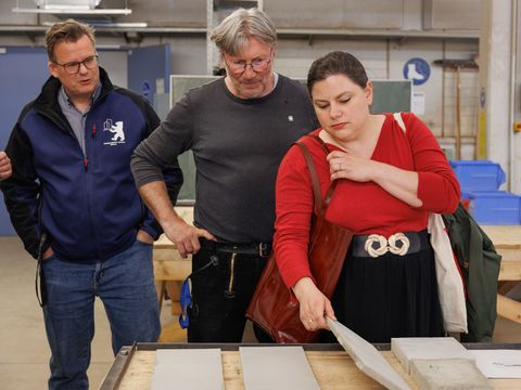 Drei Personen begutachten Beton-Stücke
