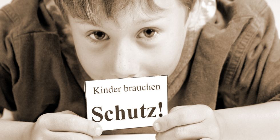 Junge mit Schild - Kinder brauchen Schutz