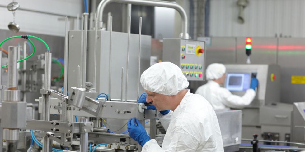 Zwei Arbeiter mit Kittel an Maschinen