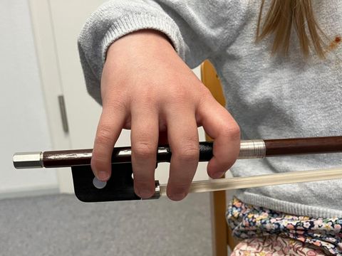 Kinderhand an Bogen
