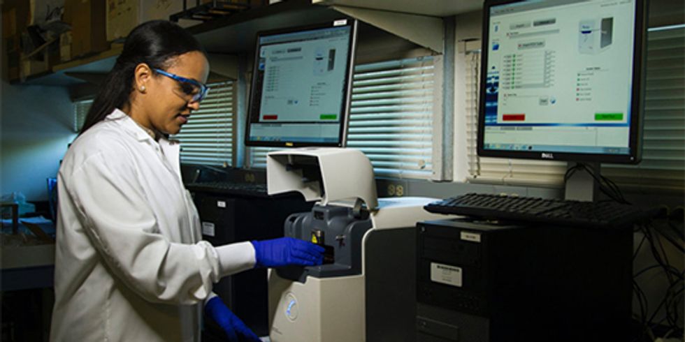 Frau im Laborkittel steht an computergesteuertem Testgerät