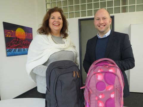 Alexander Ewers übergibt Jugendamtsdirektorin Claudia Schütz (li.) symbolisch zwei Rucksäcke. (Bild: BA Reinickendorf)