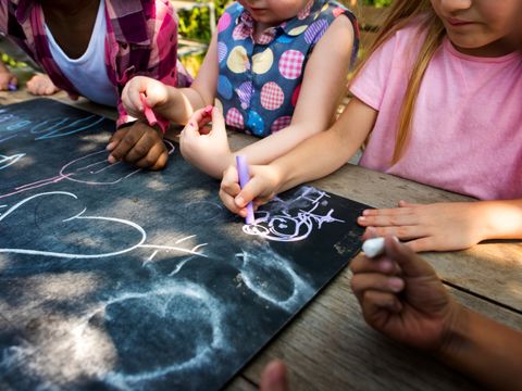 Kinder malen auf Tafel im Garten