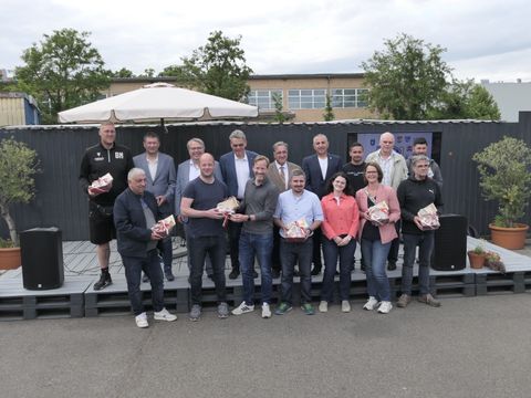 16 Frauen und Männer lächeln in die Kamera